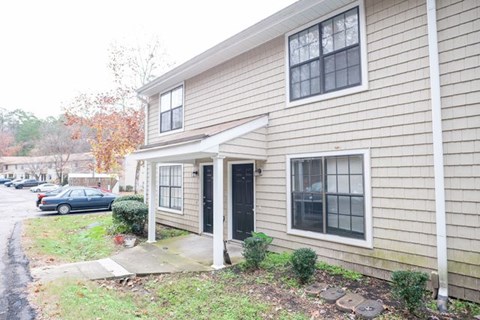 A beige house with a black door and a small porch.