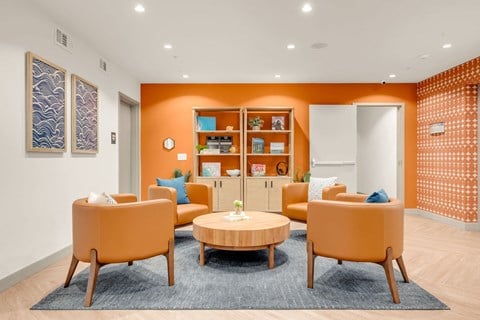 A living room with orange chairs and a round table.