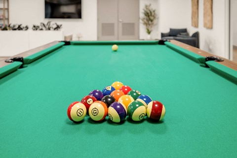 A pool table with a green cloth and a variety of pool balls.