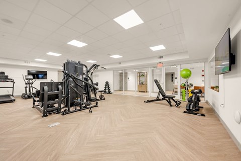 A gym with a variety of equipment including a treadmill, a stationary bike, and a weight machine.