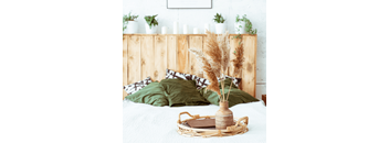 a bed with green pillows and a wooden headboard and a vase of