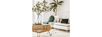 a living room with a couch and a table with a vase of flowers