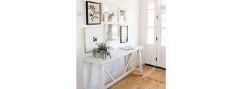 a white desk with a plant and pictures on the wall