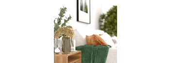 a vase with flowers on a table in a bedroom