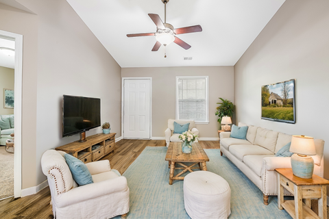 A living room with a white couch, a coffee table, and a ceiling fan.