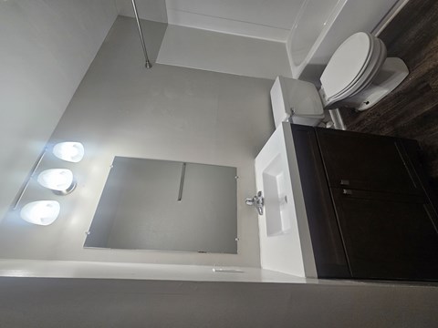A bathroom with a toilet, sink, and mirror.