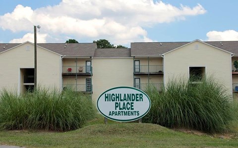 The sign in front of the building says Highlander Place Apartments.