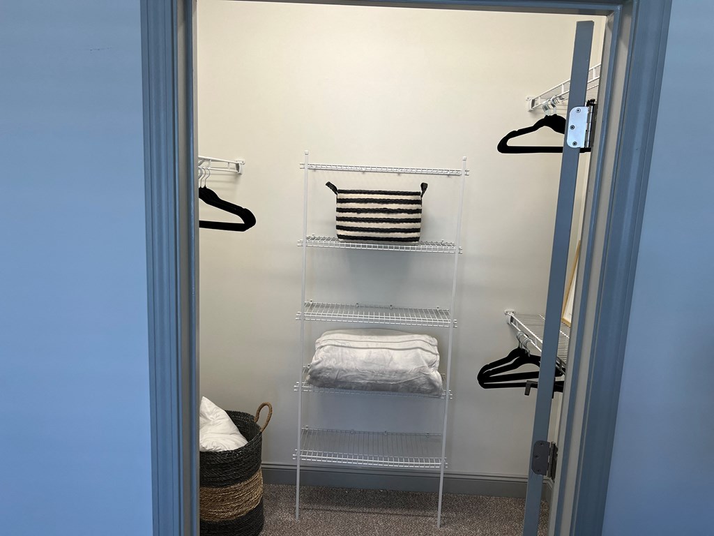 a walk in closet with white shelves and a blue door