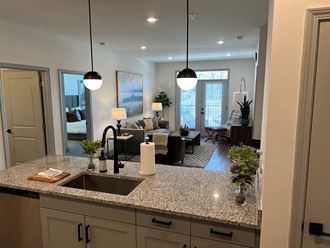 a kitchen with granite countertops and a living room in the background