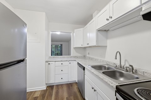 A kitchen with white cabinets and a stainless steel refrigerator.