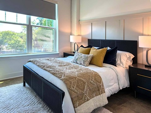 A bedroom with a large bed and a window overlooking a tree-filled area.