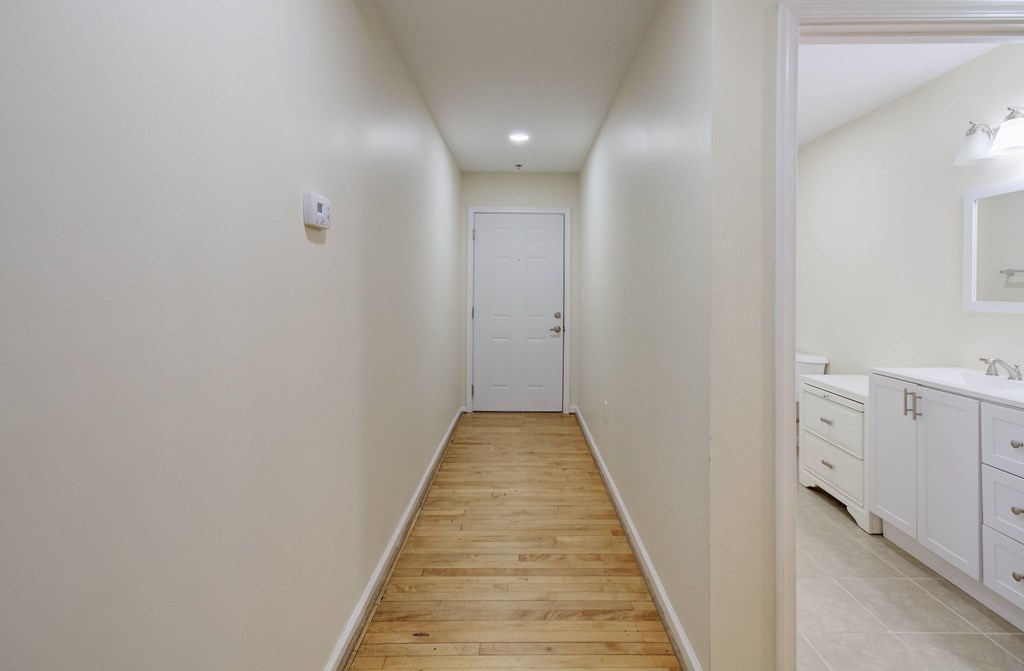 A long hallway with a white door at the end.