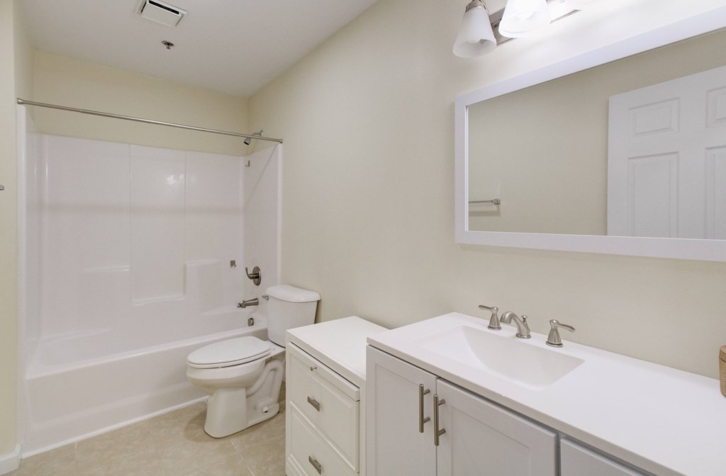 A white bathroom with a toilet, sink, and shower.