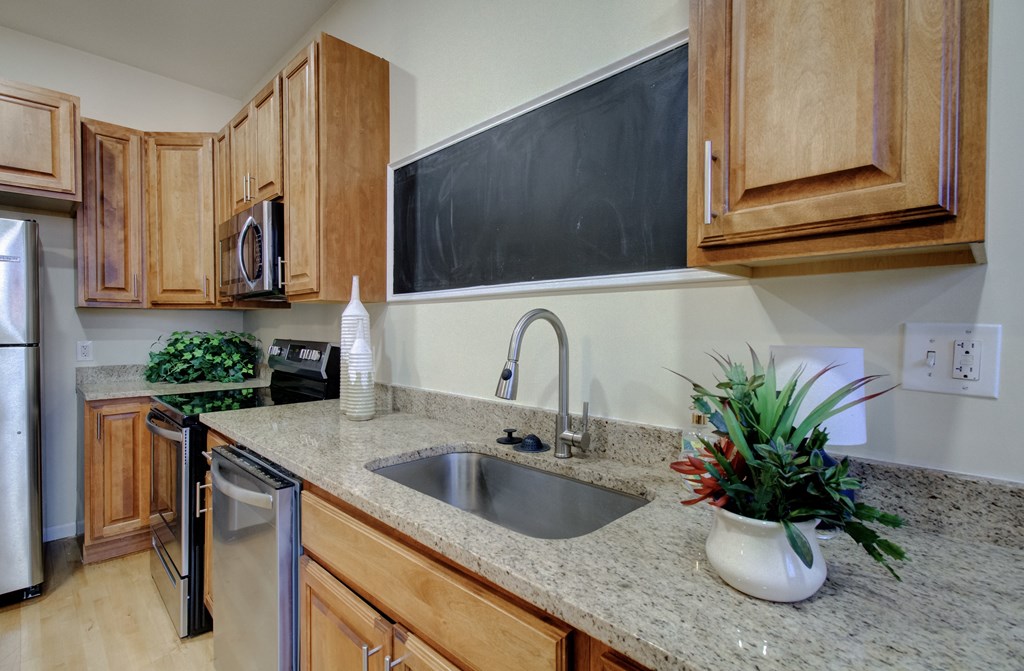 A kitchen with wooden cabinets and a blackboard on the wall.