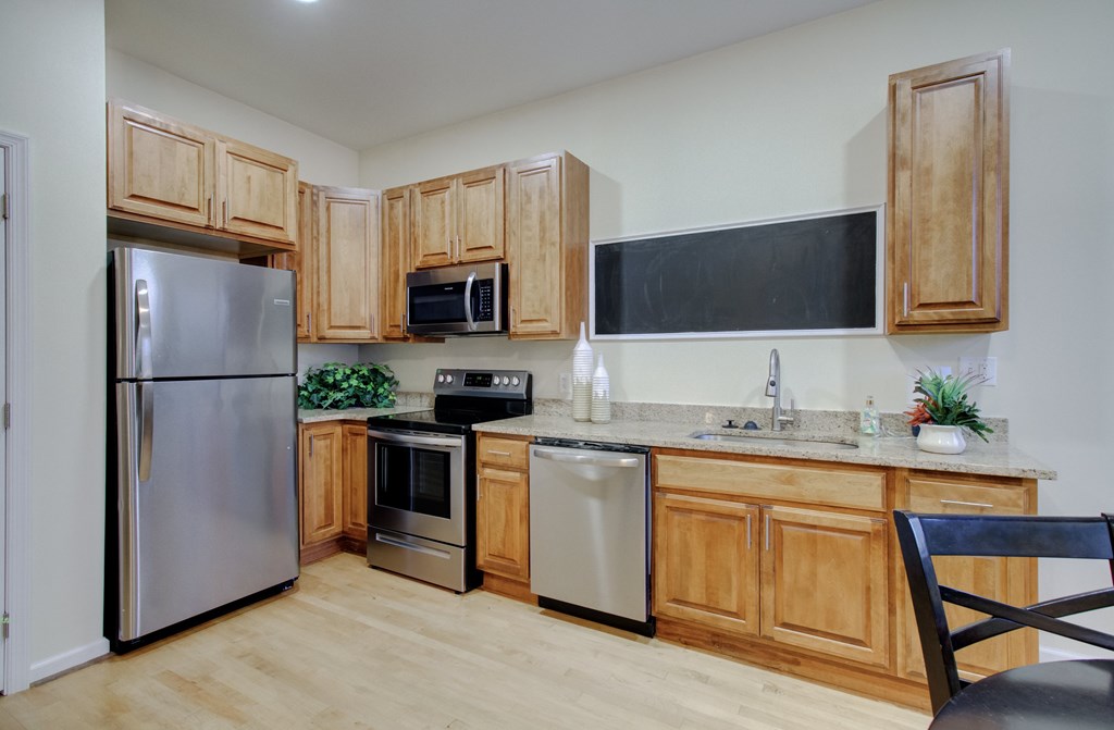 A kitchen with wooden cabinets and a stainless steel refrigerator.