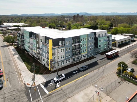 A large apartment complex is situated on a street corner with a view of the mountains in the distance.