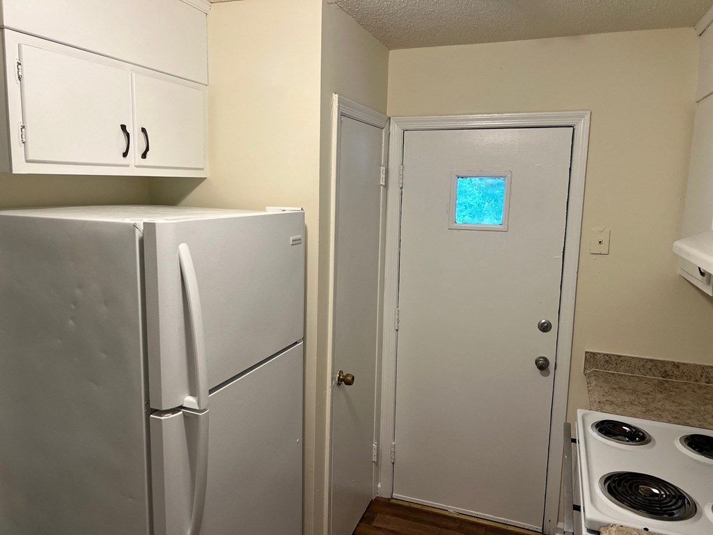 a kitchen with a refrigerator and a door with a window