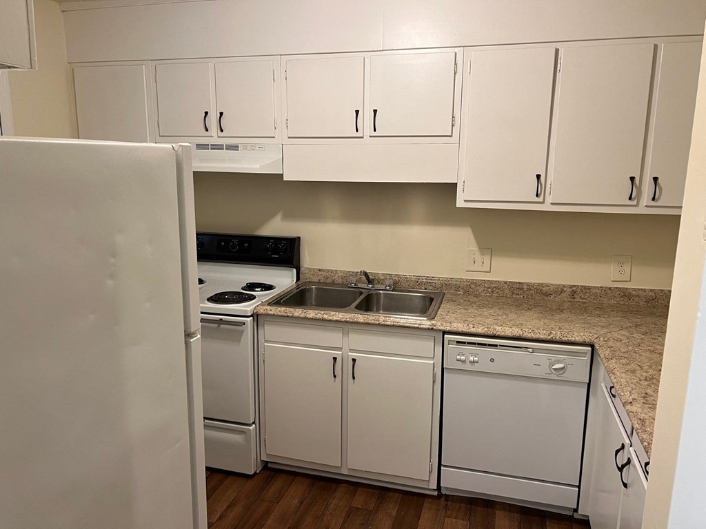 A white kitchen with a refrigerator, oven, and sink.