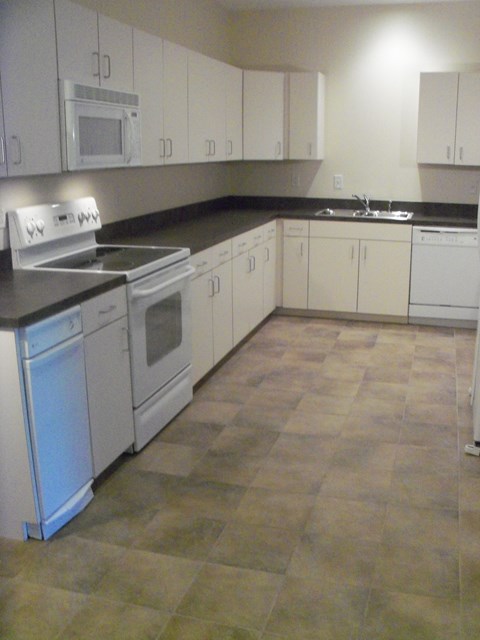 A kitchen with white cabinets and a black counter top.