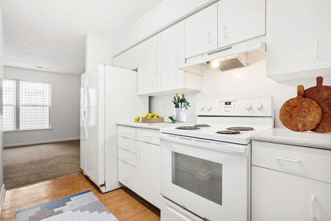 A white kitchen with a refrigerator, oven, and stove.
