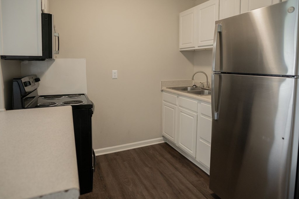 A kitchen with a stainless steel refrigerator and white cabinets.