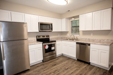 A kitchen with a stainless steel refrigerator, microwave, oven, and dishwasher.