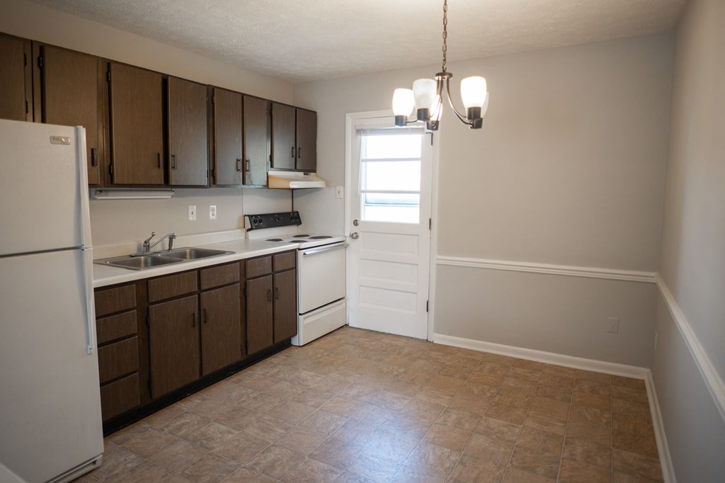A kitchen with brown cabinets and a white fridge.