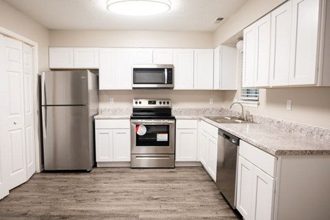 A kitchen with white cabinets and a stainless steel refrigerator.