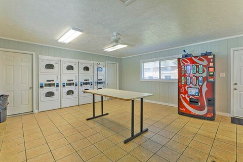 A room with a table, chairs, and a vending machine.