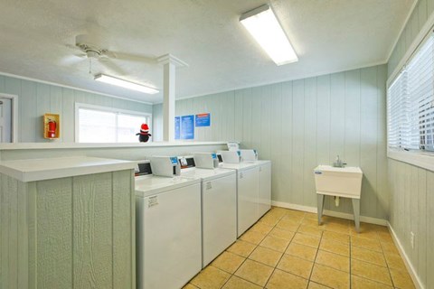 A laundry room with a washer and dryer, sink, and a window.