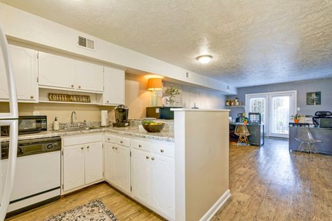 A kitchen with white cabinets and a wooden floor.