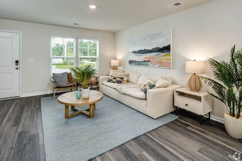 A living room with a white couch, a wooden coffee table, and a painting on the wall.