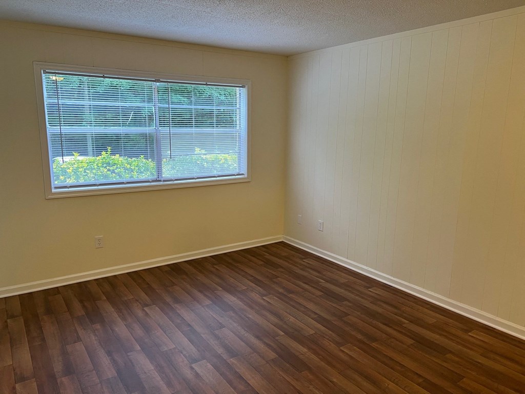 an empty living room with wood floors and a window