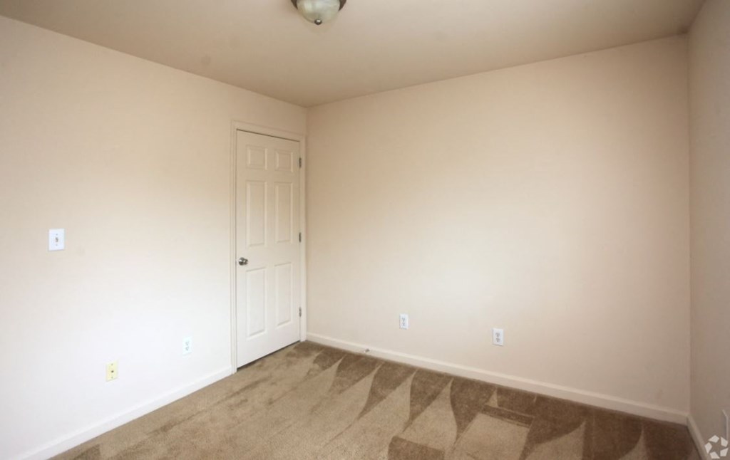 a bedroom with a door and a carpeted floor