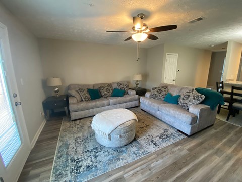 A living room with a white ceiling fan and two couches.
