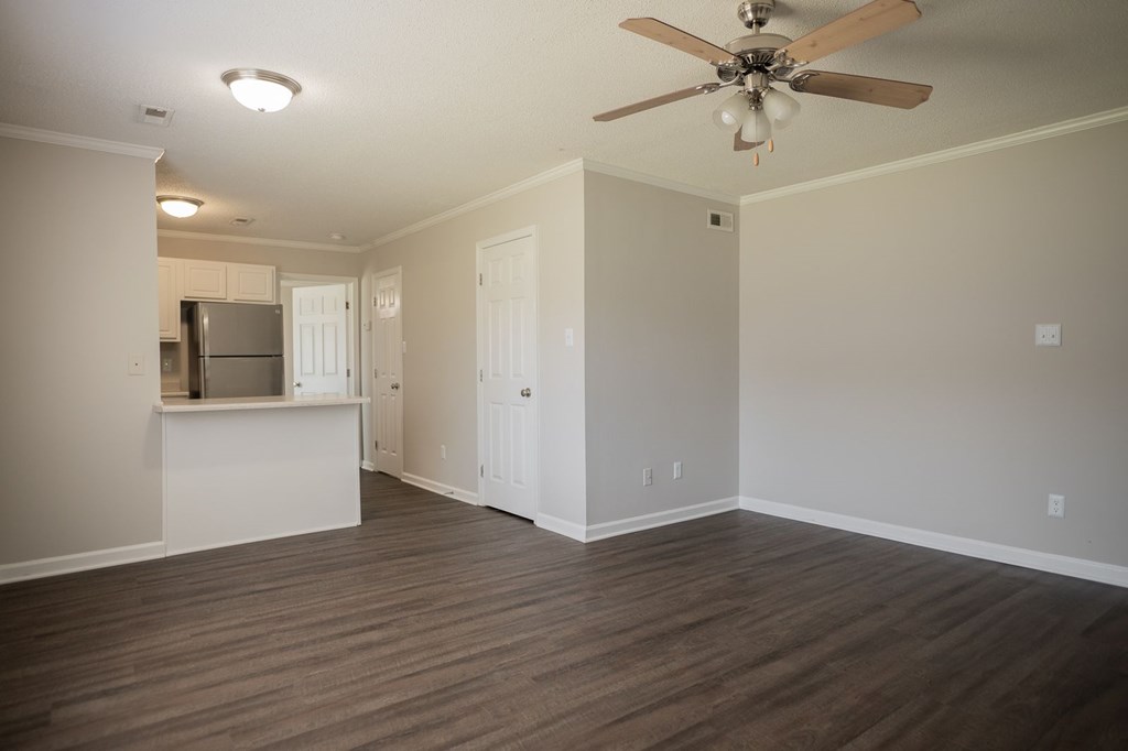 A room with a ceiling fan and wooden flooring.