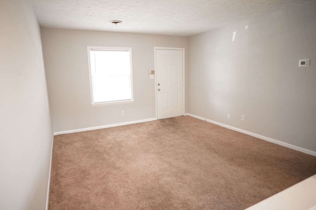 A room with a carpeted floor and a door.