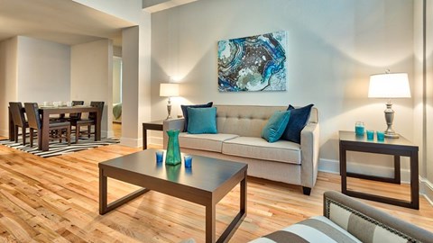 A living room with a couch, coffee table, and a painting on the wall.