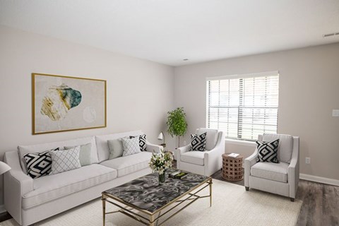A living room with a white couch, two chairs, and a coffee table.
