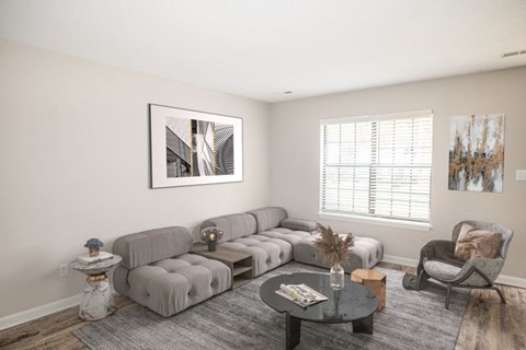 A living room with a grey sofa, a coffee table, and a painting on the wall.
