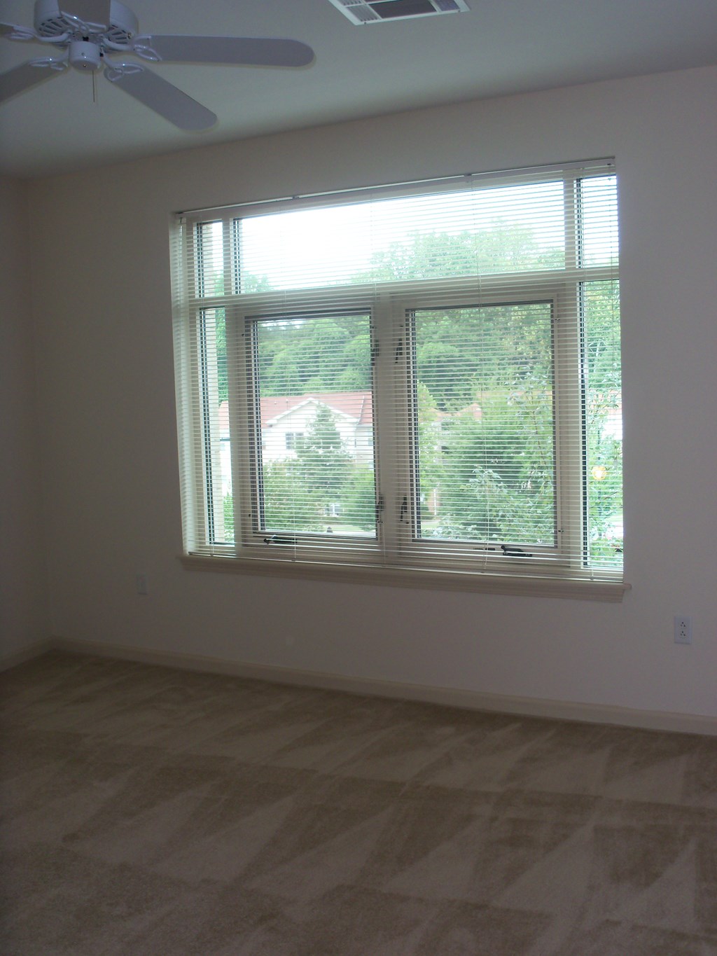 A room with a window and a ceiling fan.