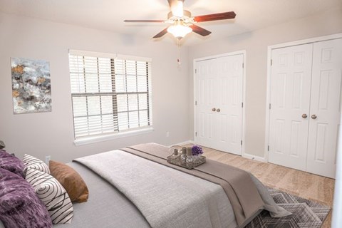 A bedroom with a bed, pillows, and a ceiling fan.
