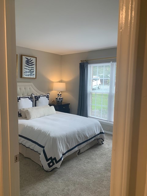 A bedroom with a large bed and a window with a view of a parking lot.