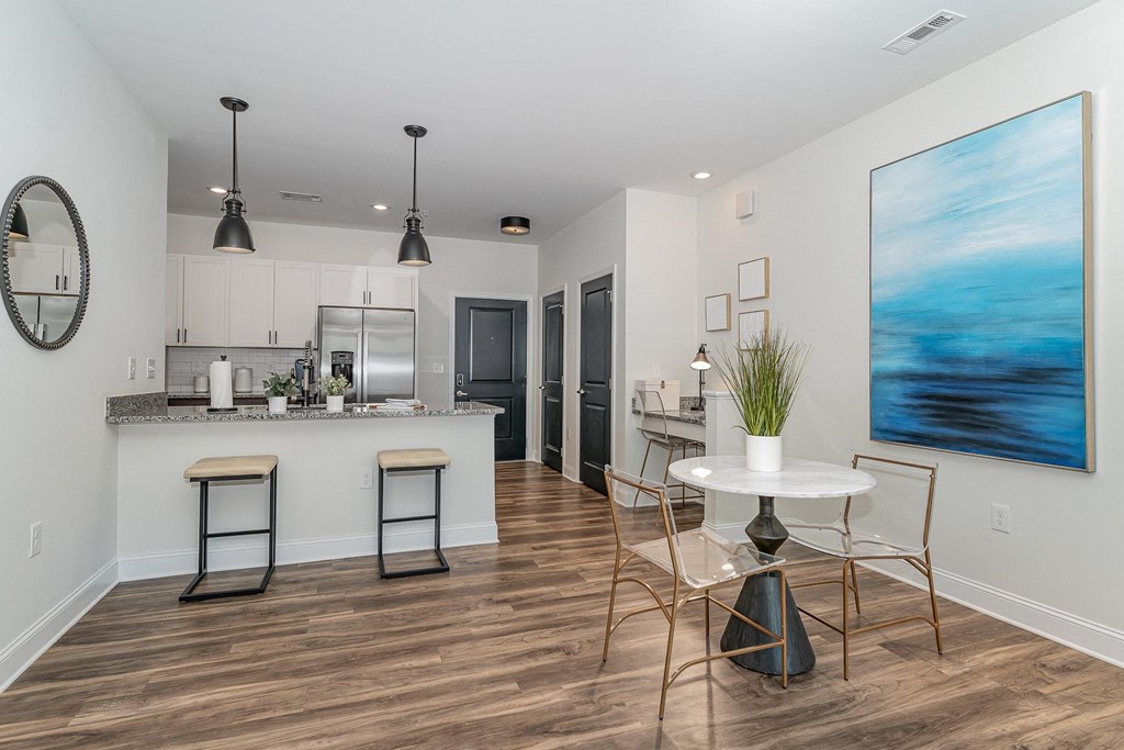 a dining area with a table and chairs and a kitchen in the background