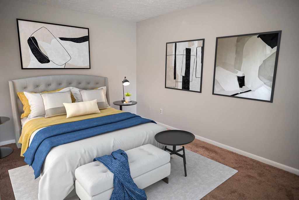 A bedroom with a bed, a chair, and two framed artworks on the wall.