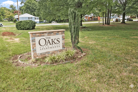 A sign for The Oaks Apartments is surrounded by a small garden.