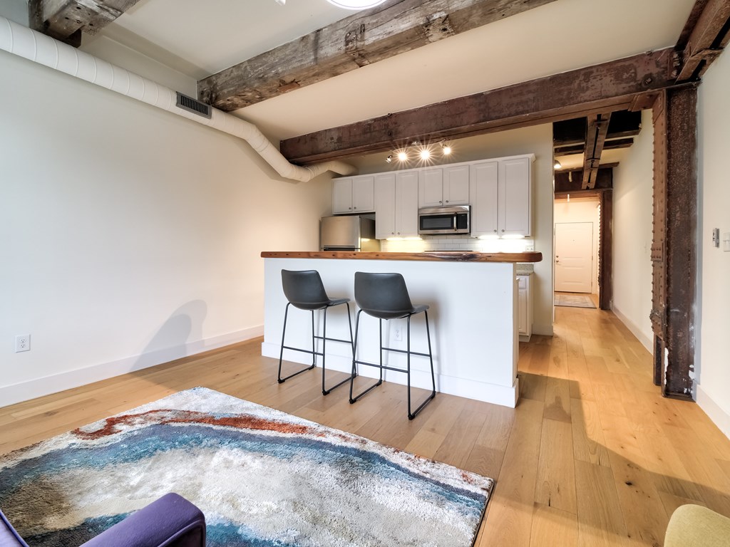 A kitchen with a bar stool and a rug in front of it.