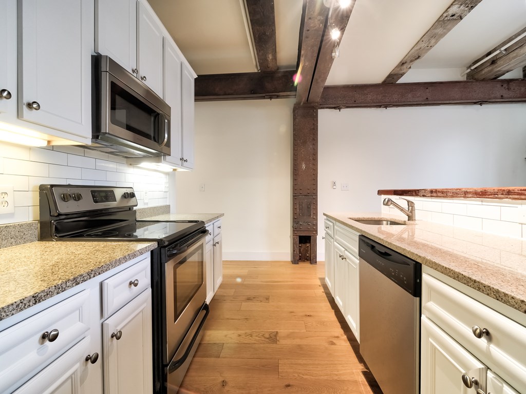 A kitchen with white cabinets and a wooden floor.