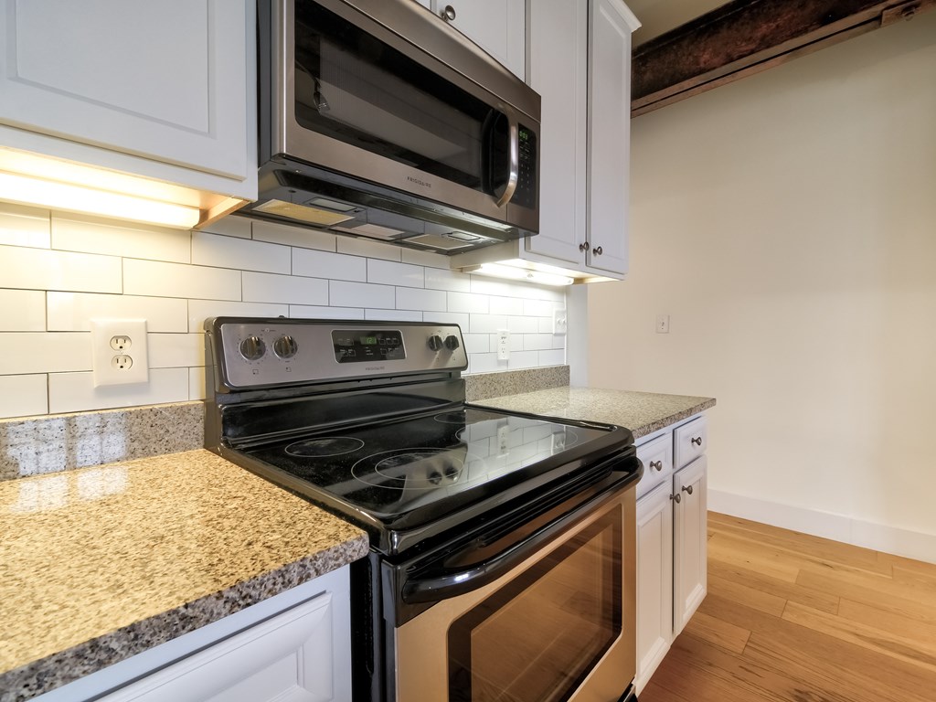 A kitchen with a black stove top oven and microwave above it.