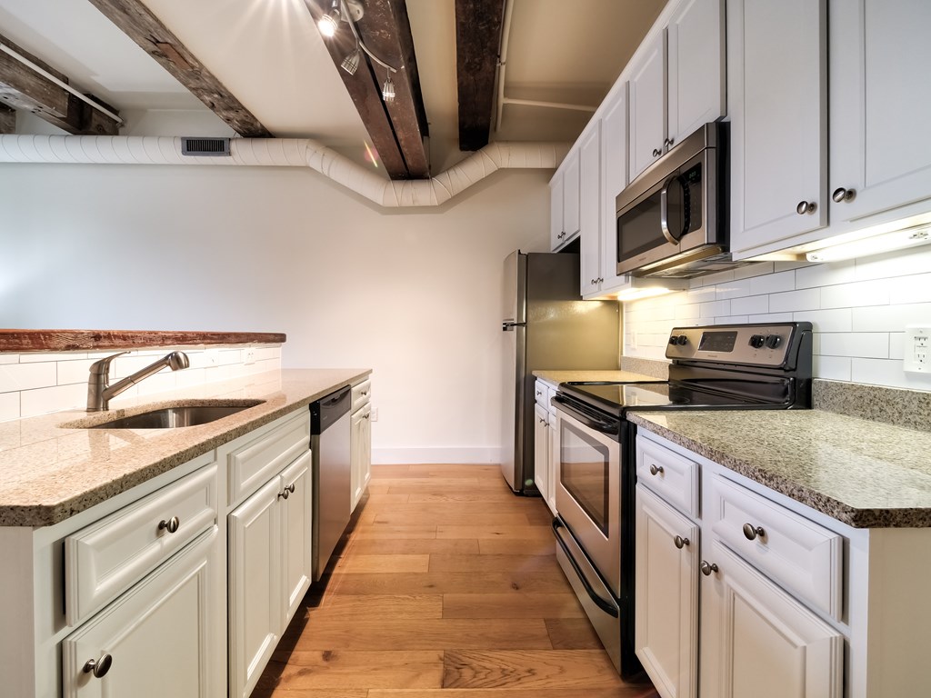 A kitchen with white cabinets and a wooden floor.